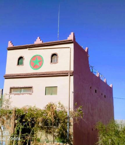 a building with a clock on the side of it at Maison d hôtes Tioute Chez Abdelmajid in Tiout