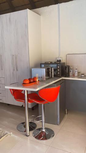 a kitchen with a table and two red chairs at Glamour C-rane lodge in Phalaborwa