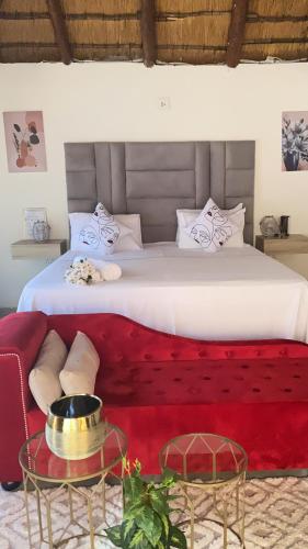 a bedroom with a large bed with a red couch at Glamour C-rane lodge in Phalaborwa
