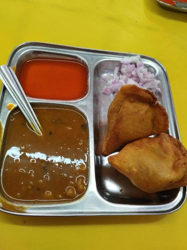 a tray of food with meat and sauce and onions at Maji Homestay Khajuraho in Khajurāho