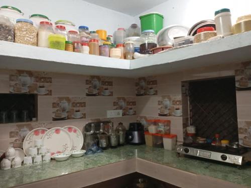 a kitchen with a counter with dishes on shelves at Maji Homestay Khajuraho in Khajurāho