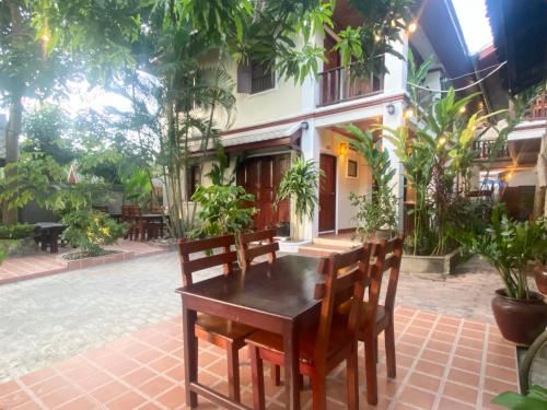 a wooden table and chairs in front of a building at Golden Sun Boutique Hotel in Luang Prabang