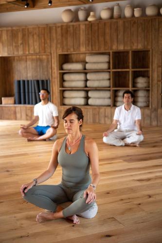 a woman sitting in a yoga pose on a wooden floor at Tigmiza Boutique Hotel & Spa in Marrakech