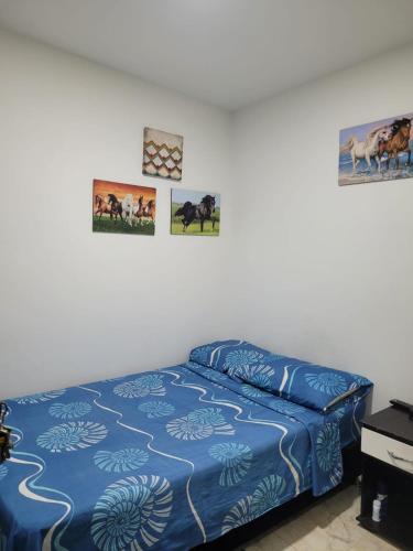 a bedroom with a bed with blue sheets and pictures on the wall at HOSTAL S Y S in Cali