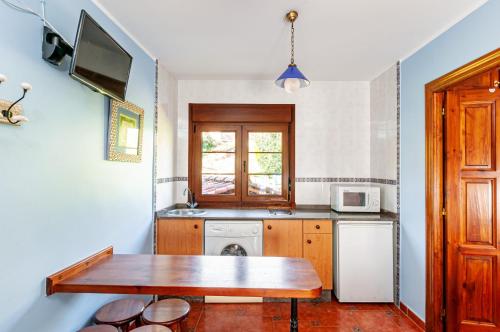 a kitchen with a wooden table and a microwave at Apartamentos la Regoria in Arenas de Cabrales
