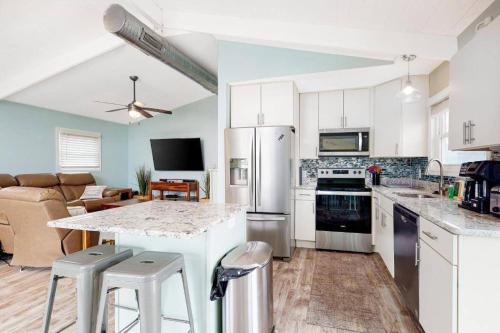 a kitchen with white cabinets and a table with bar stools at The Orange Crush - 5BR Beachfront Family Retreat in Ocean City