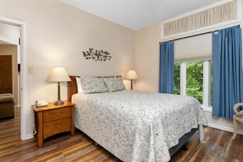 a bedroom with a bed and a window with blue curtains at Laurelwood 80 with Wintergreen Advantage in Wintergreen