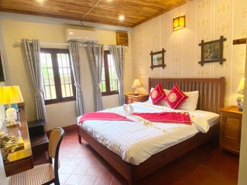a bedroom with a large bed with red pillows at Golden Sun Boutique Hotel in Luang Prabang