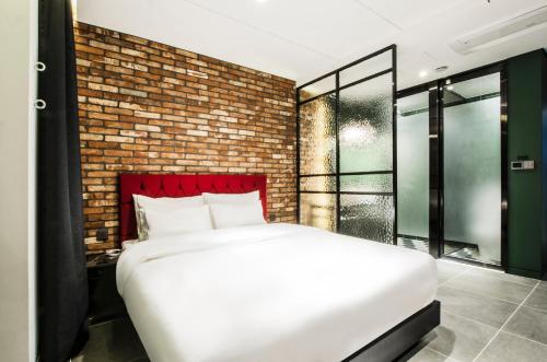 a bedroom with a white bed and a brick wall at Hotel the Castle Jamsil#1 in Seoul