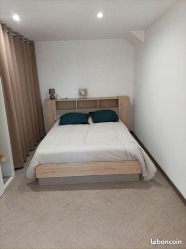 - une chambre avec un lit en bois et 2 oreillers bleus dans l'établissement Chez Sabine La Campagne, à Narbonne