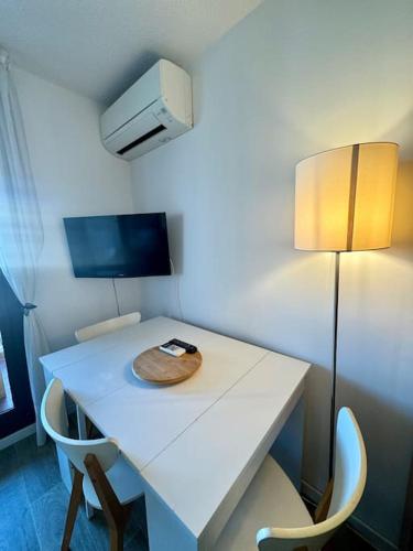 une table blanche avec deux chaises et une lampe dans l'établissement Appartement Cap d'Agde accès direct à la plage, au Cap d'Agde
