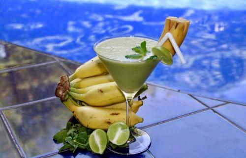 a drink sitting next to a bunch of bananas at Sundaras Infinity Jungle Resort in Dambulla