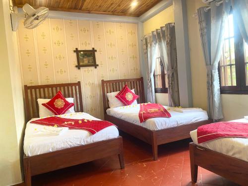 a bedroom with two beds with red pillows on them at Golden Sun Boutique Hotel in Luang Prabang