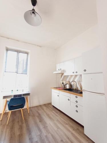 une cuisine avec des armoires blanches et un plancher en bois dans l'établissement studio proche gare, à Agen