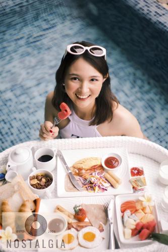 a woman sitting in a pool with a table of food at Bantique Hotel in Da Nang