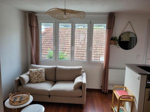 un salon avec un canapé et deux fenêtres dans l'établissement Appartement au cœur de Rambouillet, à Rambouillet