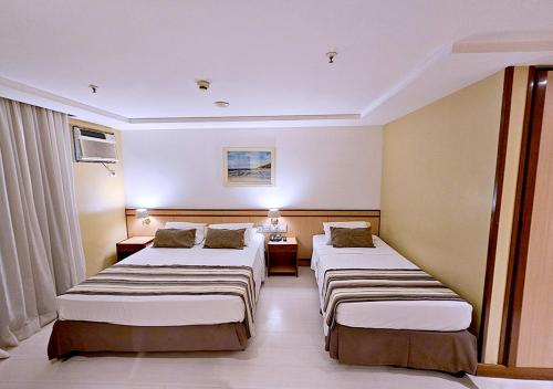 a room with three beds in a hotel room at Riale Vilamar Copacabana in Rio de Janeiro