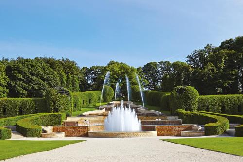 a fountain in the middle of a garden with hedges at Cosy Alnwick Apartment in Alnwick