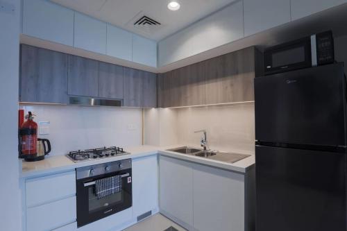 a kitchen with a black refrigerator and a sink at Chic 1 Bedroom in Privé Residence, Dubai Hills in Dubai