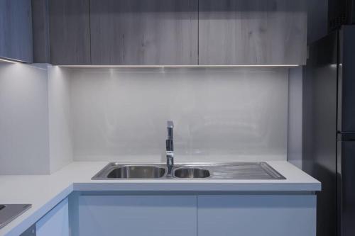 a white kitchen with a sink and a refrigerator at Chic 1 Bedroom in Privé Residence, Dubai Hills in Dubai