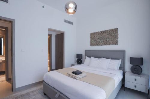 a bedroom with a large white bed with a lamp at Chic 1 Bedroom in Privé Residence, Dubai Hills in Dubai