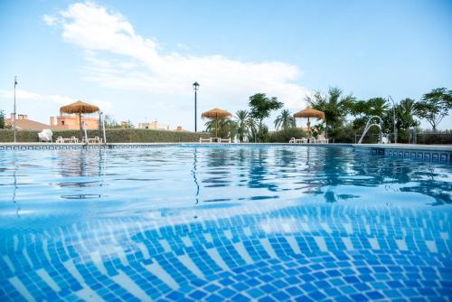- une piscine d'eau bleue avec des parasols dans l'établissement Villa Arroyovil 29 y 30, à Mancha Real