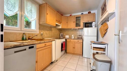 - une cuisine avec des placards en bois et des appareils blancs dans l'établissement Magnifique Appartement 9min Disney, à Bailly-Romainvilliers