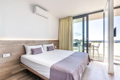 a bedroom with a large bed and a balcony at Aparthotel Comtat Sant Jordi in Platja  d'Aro
