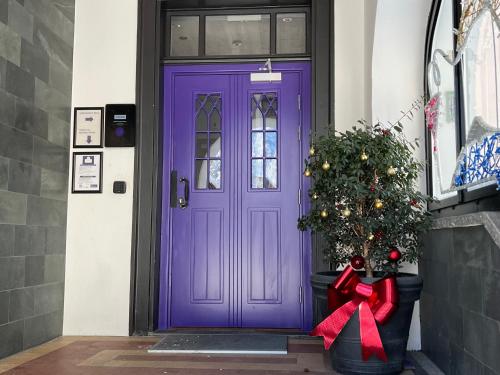 a purple door with a christmas tree and a bow at GRAND your home with common kitchens with self check-in in Engelberg
