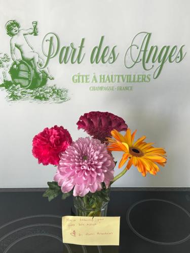 a vase of flowers on a table with a card at Part des Anges - Gîte Hautvillers in Hautvillers