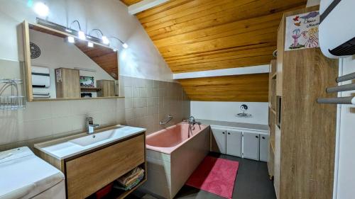 La salle de bains est pourvue d'un lavabo et d'une baignoire rose. dans l'établissement Duplex Serre-Chevalier Briançon, à Briançon