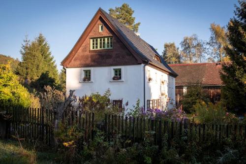 a white house with a brown roof behind a fence at ENJOY COZY NEST View Hills Garden Forest Sauna Hottub in Jablonné v Podještědí