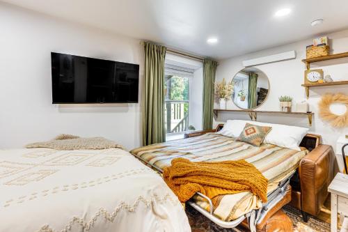 two beds in a room with a tv on the wall at Lovers Lane Chalet Dtwn Manitou Springs Studio! in Manitou Springs