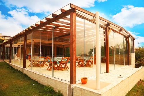 a glass house with tables and chairs on a patio at Chalé com Piscina Aquecida - Vista Panorâmica da Praia, a 200m do Mar, Sala de Jogos, Academia e Churrasqueira in Imbituba