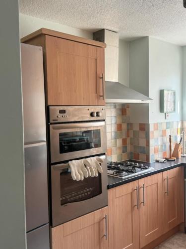 a kitchen with wooden cabinets and an oven with at Komegloba Exquisite room in Manchester