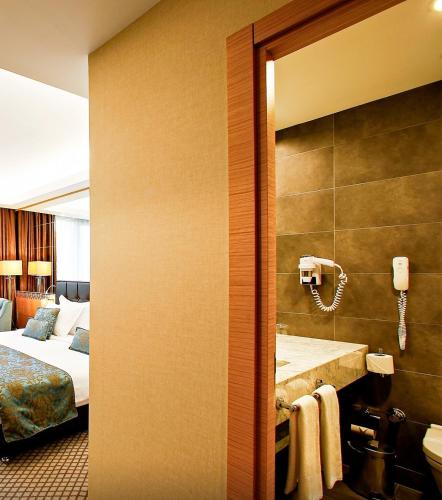 a hotel room with a bathroom with a bed and a phone at Anemon Bursa Gönlüferah Termal&Spa Otel in Bursa