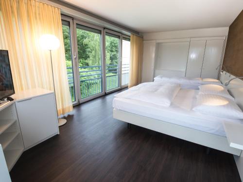 a bedroom with a large bed and a balcony at Park Hotel Zug in Zug