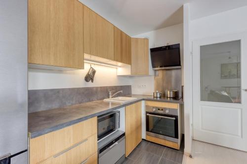 a kitchen with wooden cabinets and a sink at T2 Jardin cosy et lumineux proche Paris in Bezons