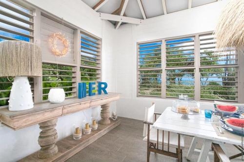 a dining room with a table and chairs and windows at Villa moderne avec piscine à Le Vauclin in Le Vauclin