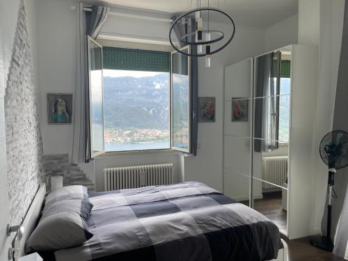 a bedroom with a bed and a large window at Appartamenti Lago di Como in Valbrona