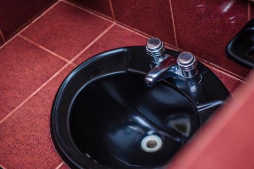 a black sink with a faucet in a bathroom at Hotel Espor CA in Barinas