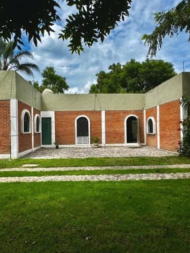 a brick building with a green door and grass at Casa Solares descanso ideal in Atlixco