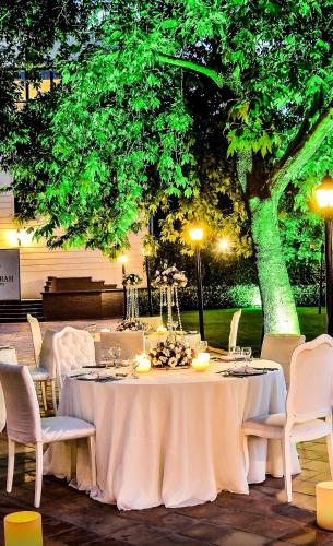 a table with a white table cloth and chairs and a tree at Anemon Bursa Gönlüferah Termal&Spa Otel in Bursa