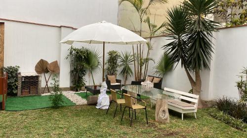 a patio with a glass table with chairs and an umbrella at Hermosa habitación independiente cerca a Miraflores in Lima