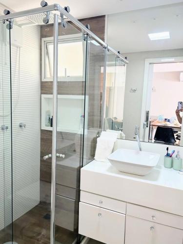 a bathroom with a glass shower and a sink at Apartamento de Luxo em Guarapari in Guarapari