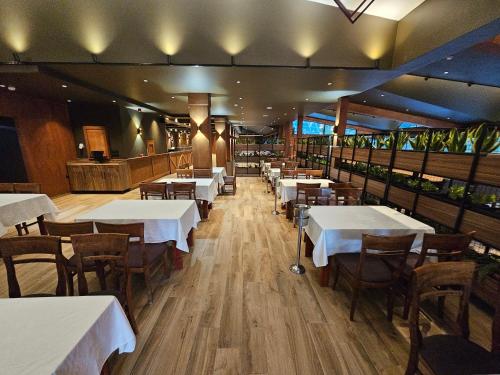 a dining room with white tables and wooden chairs at Grand Chamois Hotel & Spa in Mavrovo