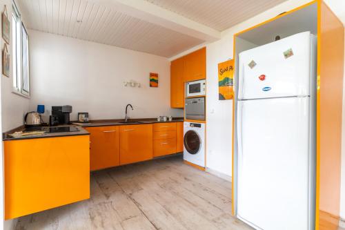 a kitchen with orange cabinets and a white refrigerator at Domaine Madinina in Le Morne-Vert