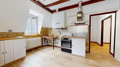 une cuisine avec des armoires blanches et un plancher en bois dans l'établissement Le Carré Mulhousien, à Mulhouse