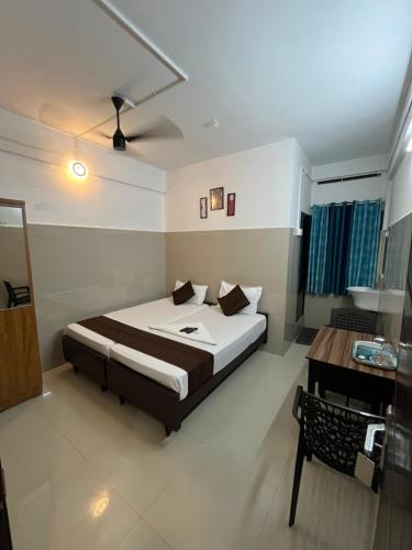 a bedroom with a bed and a desk in it at Priya lodge in Kozhikode