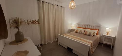 a white bedroom with a bed and two night stands at Sea & Sky townhouses in Marsaxlokk